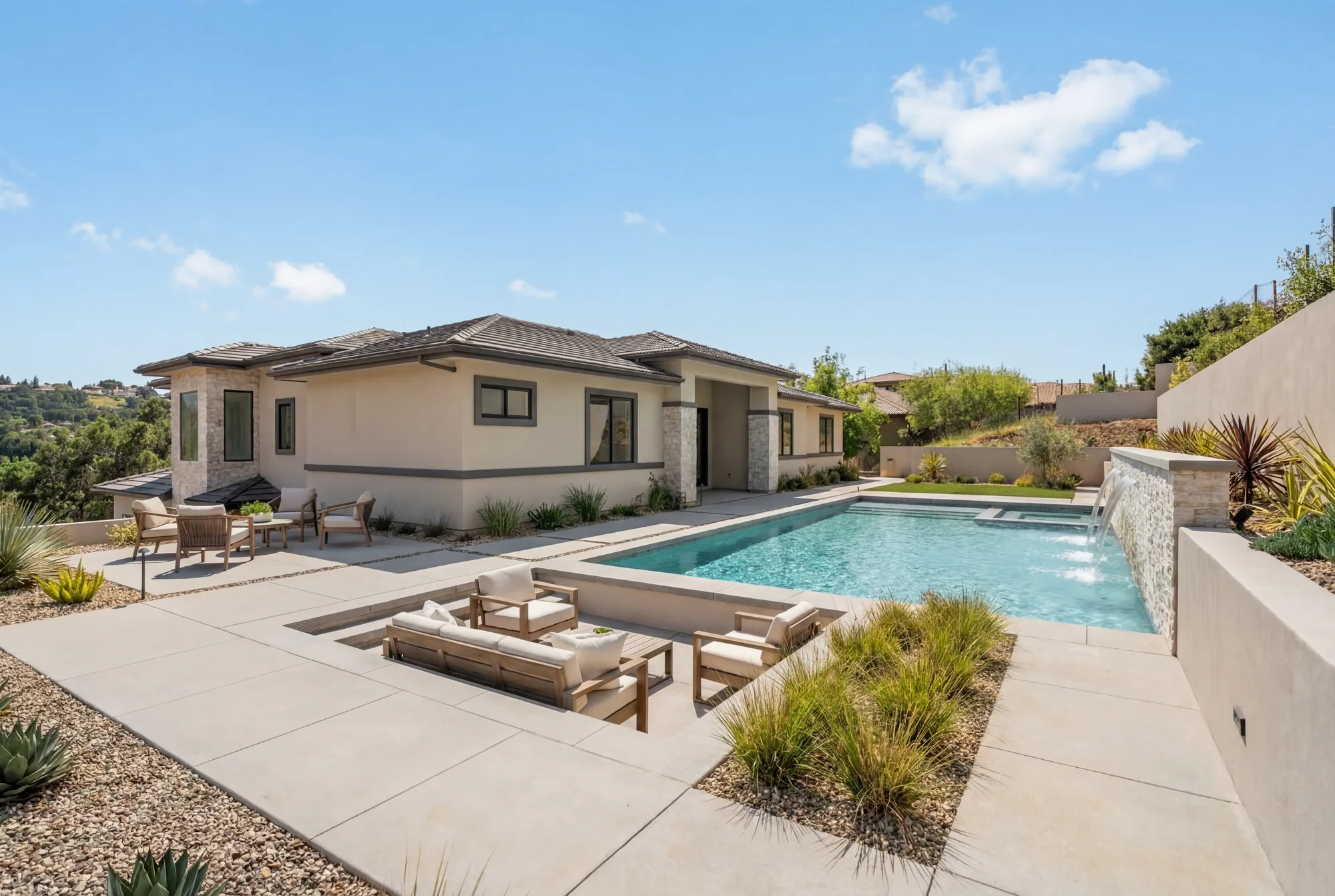 The same rear elevation as conceived: pool and spa, a sunken lounge, and paved terrace against the hillside