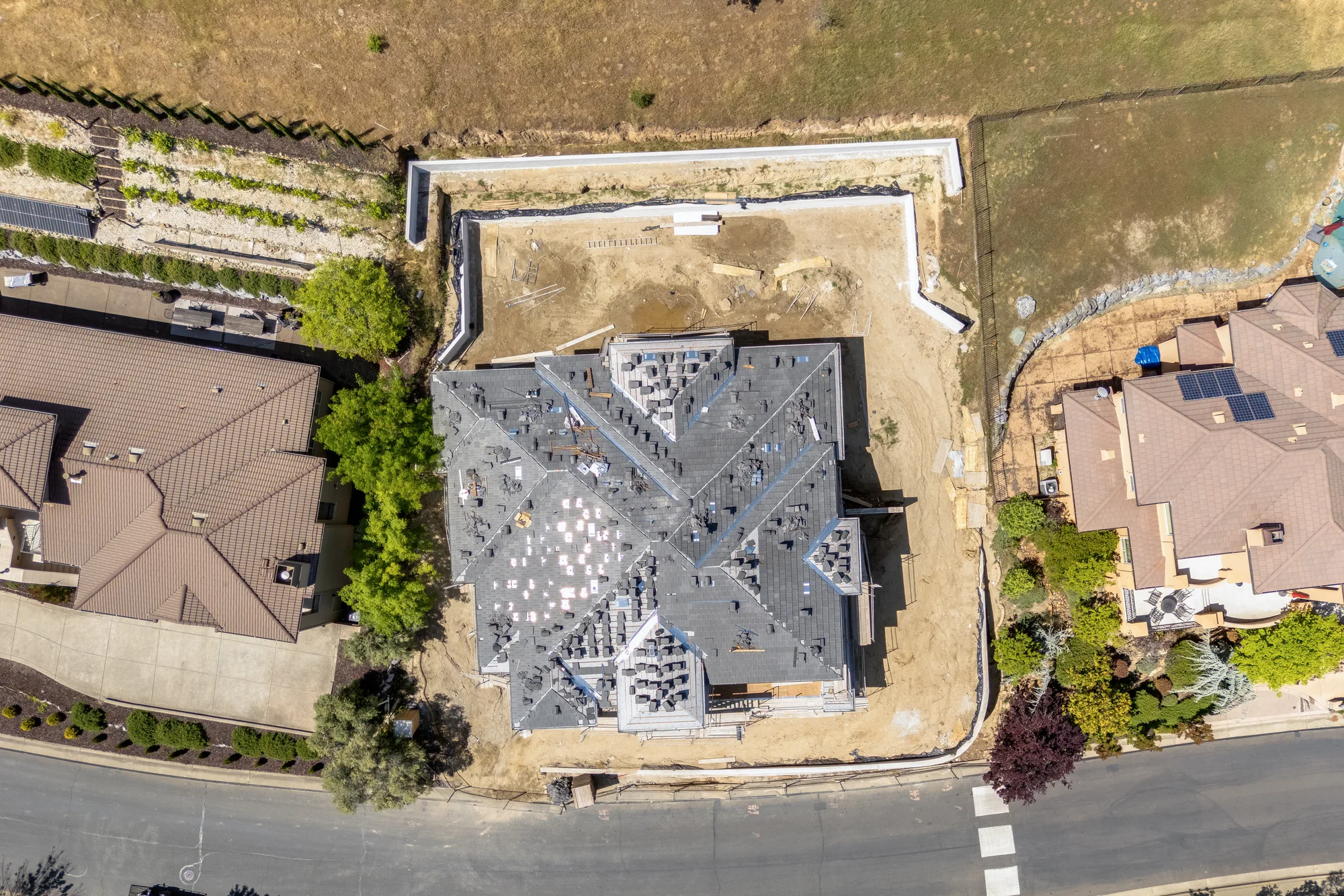 2578 Clubhouse Drive West from directly overhead in April 2026: the roof framed and papered, the lot graded to bare dirt, neighbouring homes finished on either side