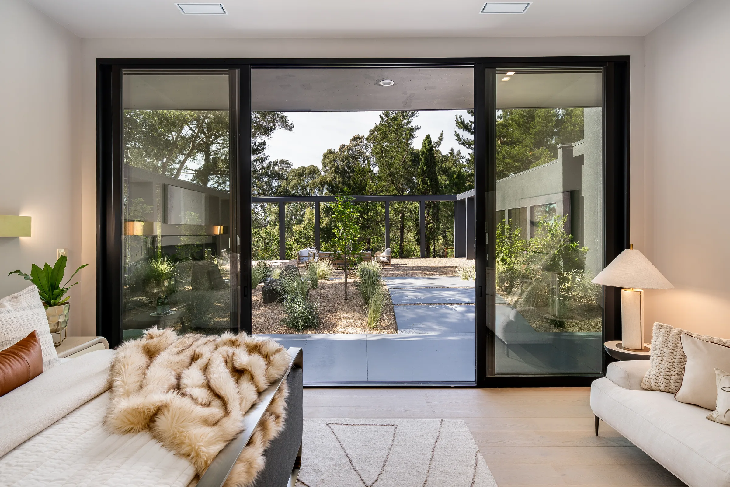 A calm sitting room at 5645 Bacon Road looking through an open slider onto the restored courtyard