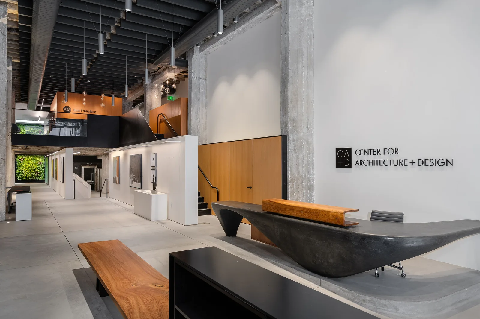 The Center for Architecture + Design in San Francisco: a sculpted concrete reception desk and gallery corridor beneath exposed structure