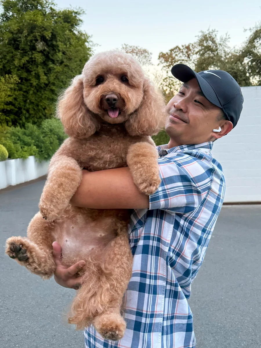 Mike holding Nia up in a parking lot, both looking at the camera.