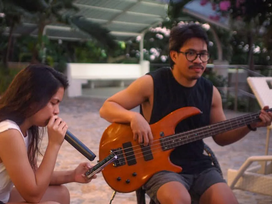 Nico playing bass beside a singer at an outdoor rehearsal.
